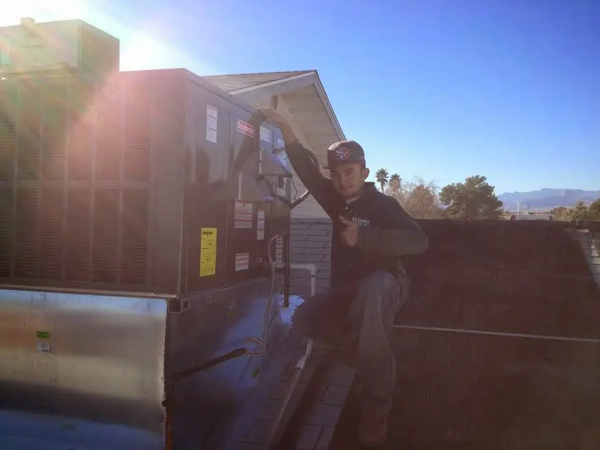 HVAC technician performing AC Tune-Up on a rooftop unit in Pass Christian