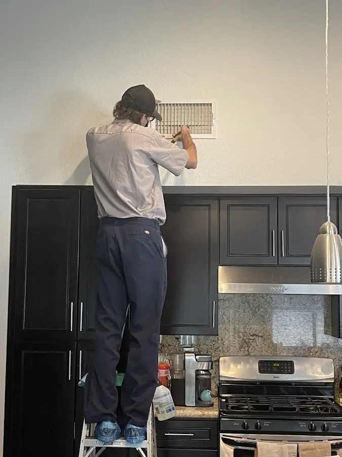 Technician inspecting an air vent during HVAC service in Pass Christian